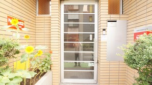 Une entrée d’immeuble avec un mur recouvert de carreaux, une porte dotée d’une fenêtre et une enseigne.