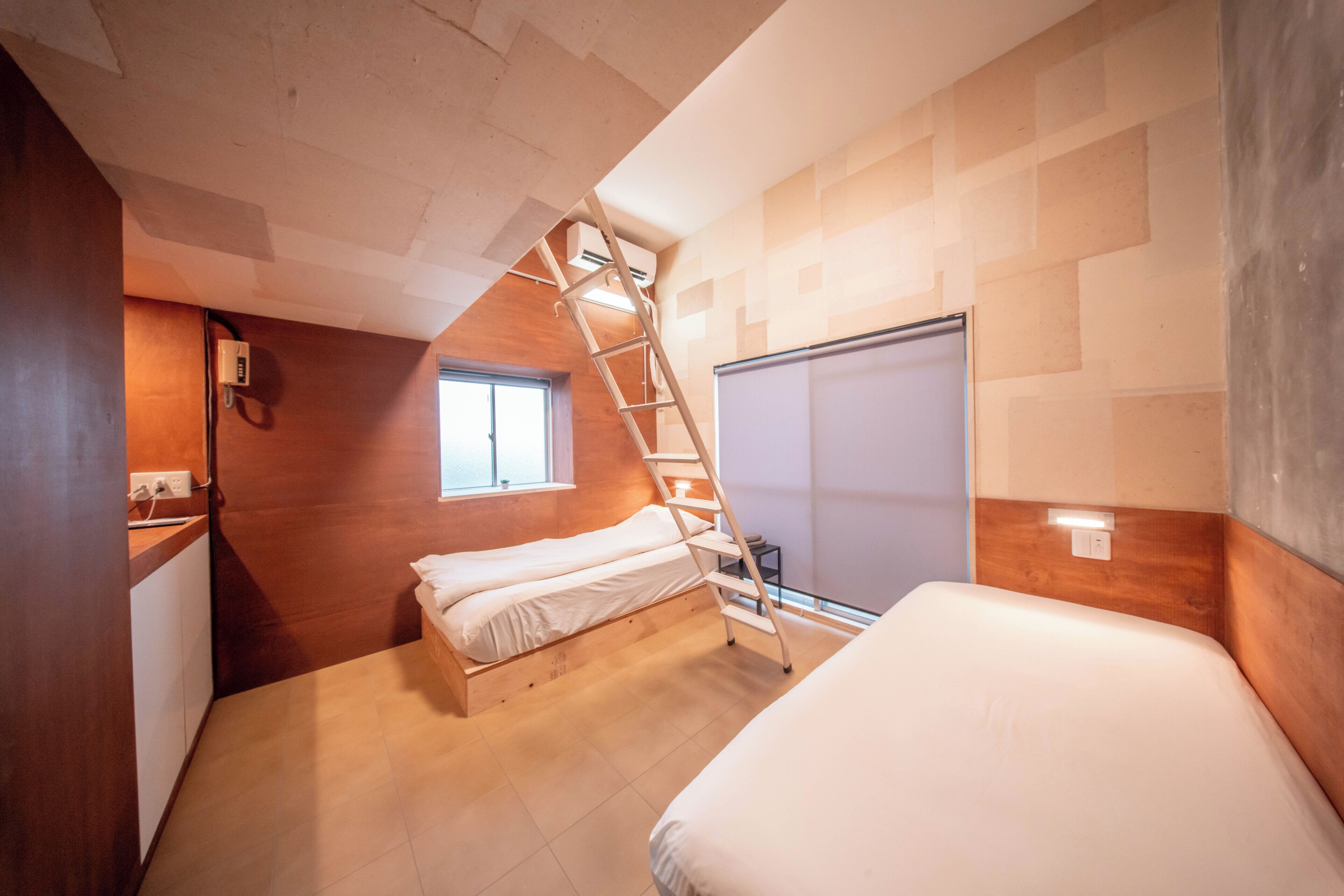 Un dormitorio con cama alta, una escalera, una ventana y un armario.