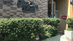 Une enseigne de l’hôtel PlusOne Fujisaki sur un mur de briques.