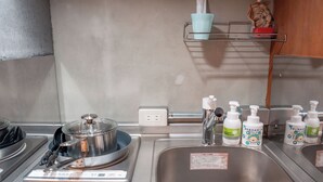 Une cuisine équipée d’une cuisinière, d’un évier et d’une balance. On peut voir des bouteilles de savon liquide sur le comptoir.