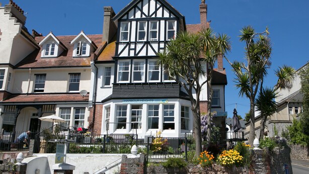 A traditional Tudor-style building with a bay window, stone walls, and a small garden with flowers. - Harbour Heights Guest House (Torquay)