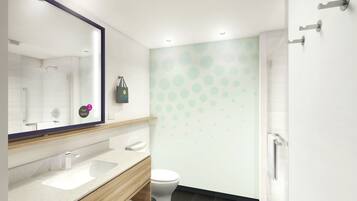 A modern bathroom with a large mirror, a wooden vanity, a white toilet, and a shower area.