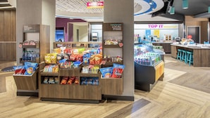 A snack display area with various packaged snacks and a beverage dispenser. - Tru by Hilton Salt Lake City Midvale (Midvale)