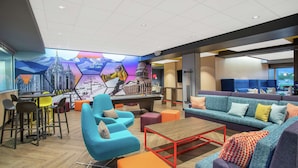A modern lounge area with a pool table, colorful seating, and a mural depicting a cityscape. - Tru by Hilton Salt Lake City Midvale (Midvale)