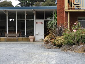A building with a sign reading "OFFICE" and a bench outside. - Somerset Caravan Park (Somerset)