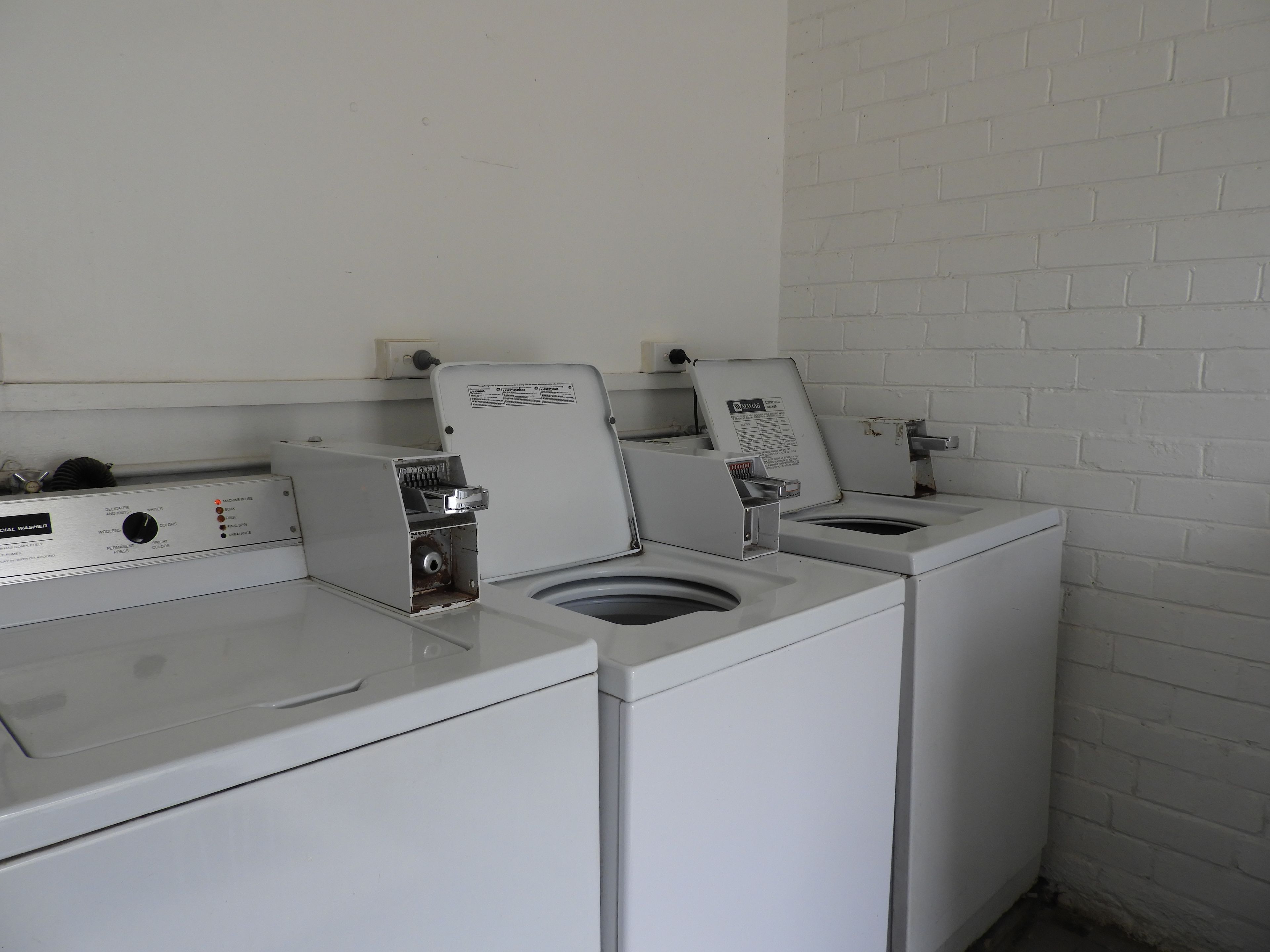A laundry facility with two washing machines and a dryer.