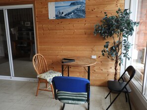 A wooden-paneled room with a round table, two chairs, a potted plant, and a poster on the wall. - Somerset Caravan Park (Somerset)