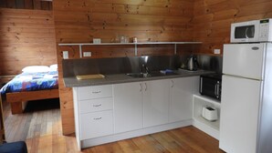 Una cocina compacta con paredes de madera, una cama y un refrigerador.