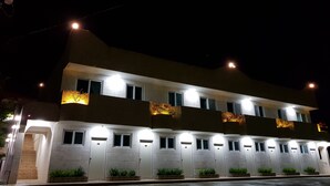 Ein mehrstöckiges Hotel mit beleuchteten Fenstern und Türen, einem flachen Dach und befestigtem Untergrund.