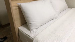 Ein zweistabliges Bett aus Holz mit weißer Bettwäsche.