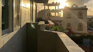 Ein Balkon mit Blick auf ein Gebäude und den Sonnenuntergang.