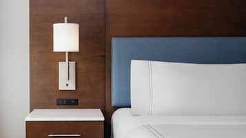 A hotel room with a wooden headboard, a bedside table with a lamp, a drawer, and a bed with white bedding.