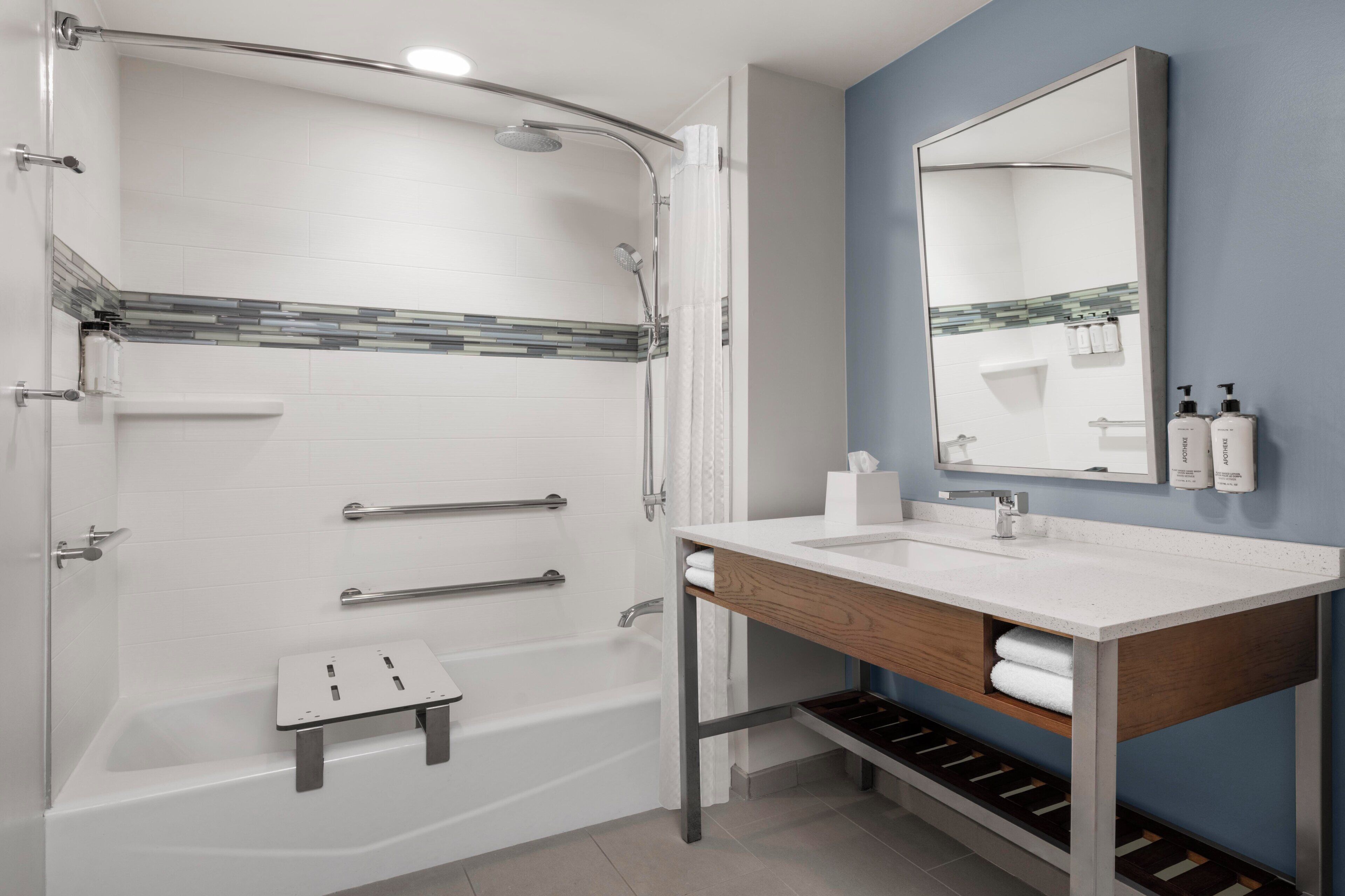 A modern bathroom with a shower, a sink, and a mirror.