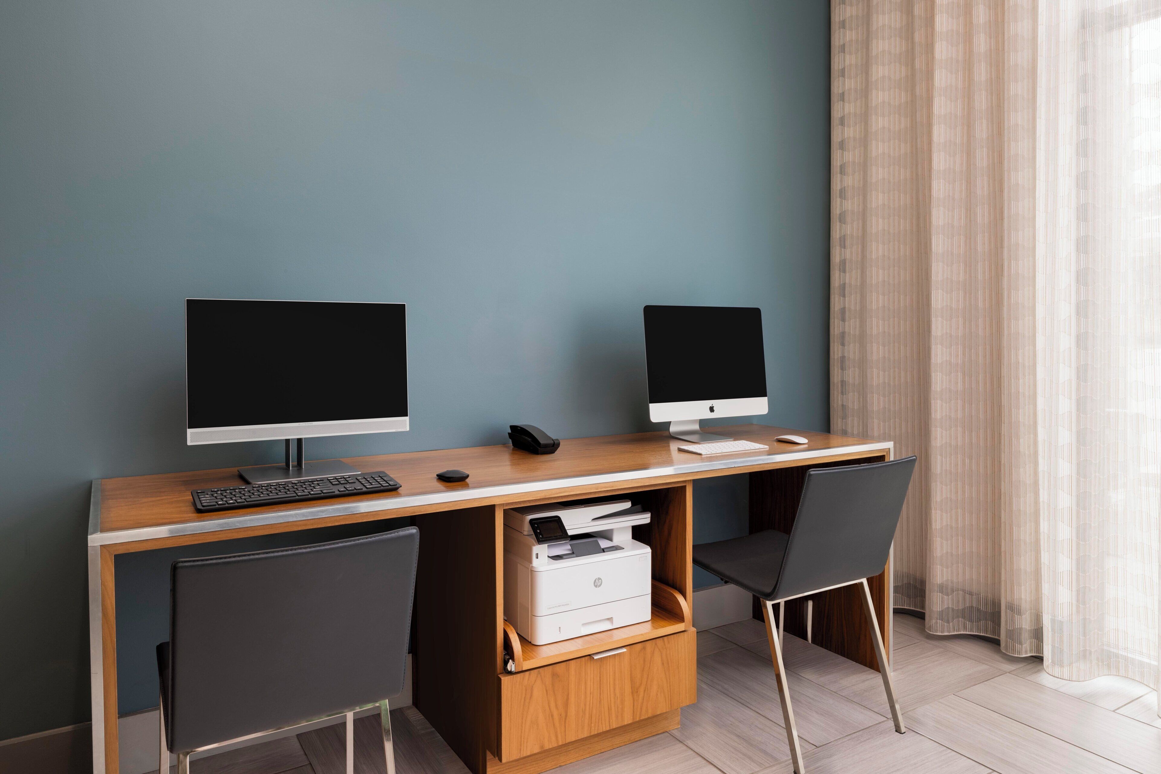 A workspace with two monitors, a keyboard, a printer, and two chairs.