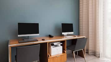 A workspace with two monitors, a keyboard, a printer, and two chairs.