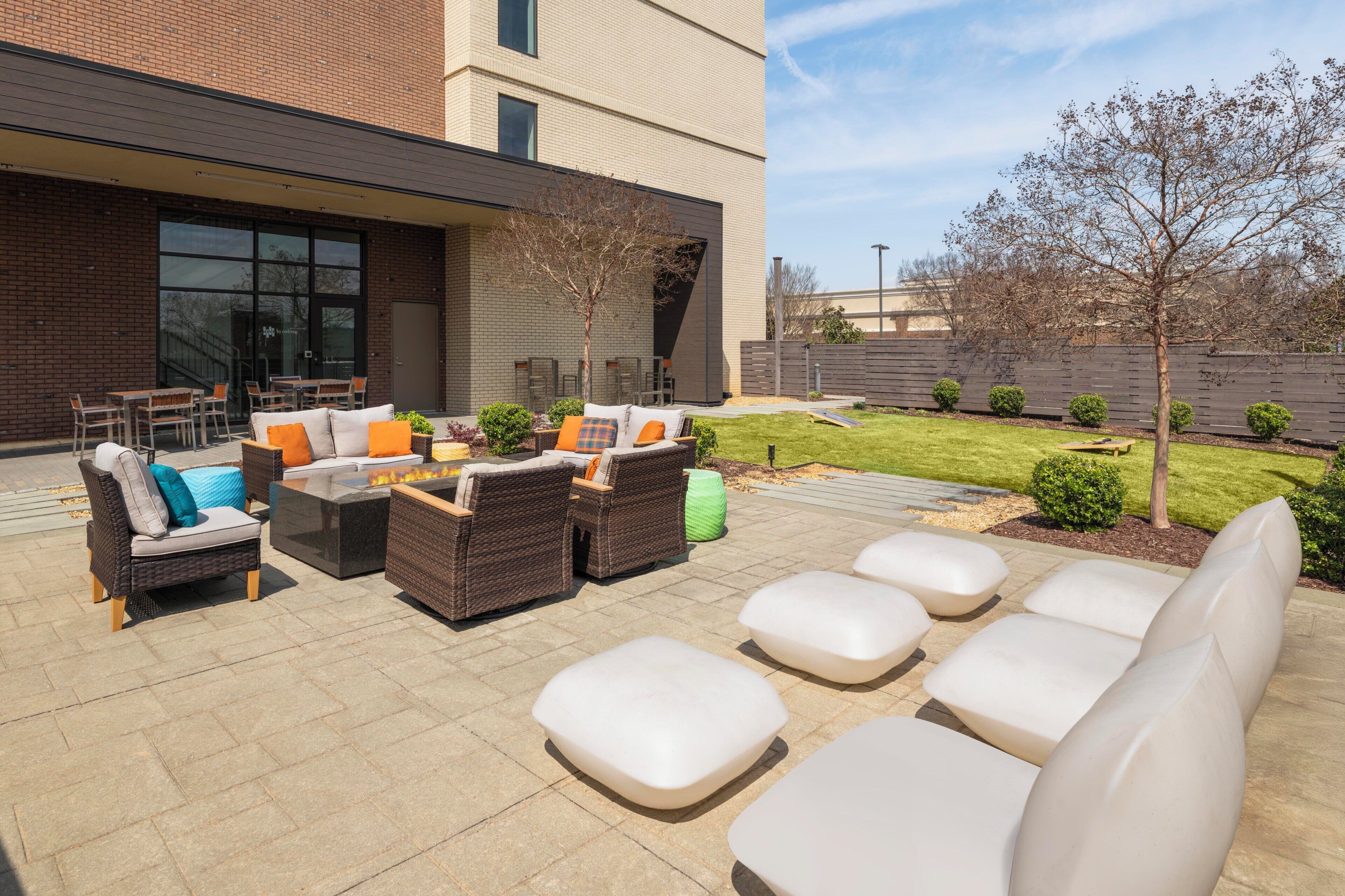 Un patio al aire libre con mobiliario de mimbre, un hogar y vistas de un edificio moderno.