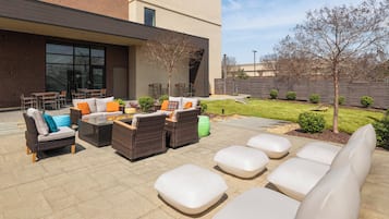 Un patio al aire libre con mobiliario de mimbre, un hogar y vistas de un edificio moderno.