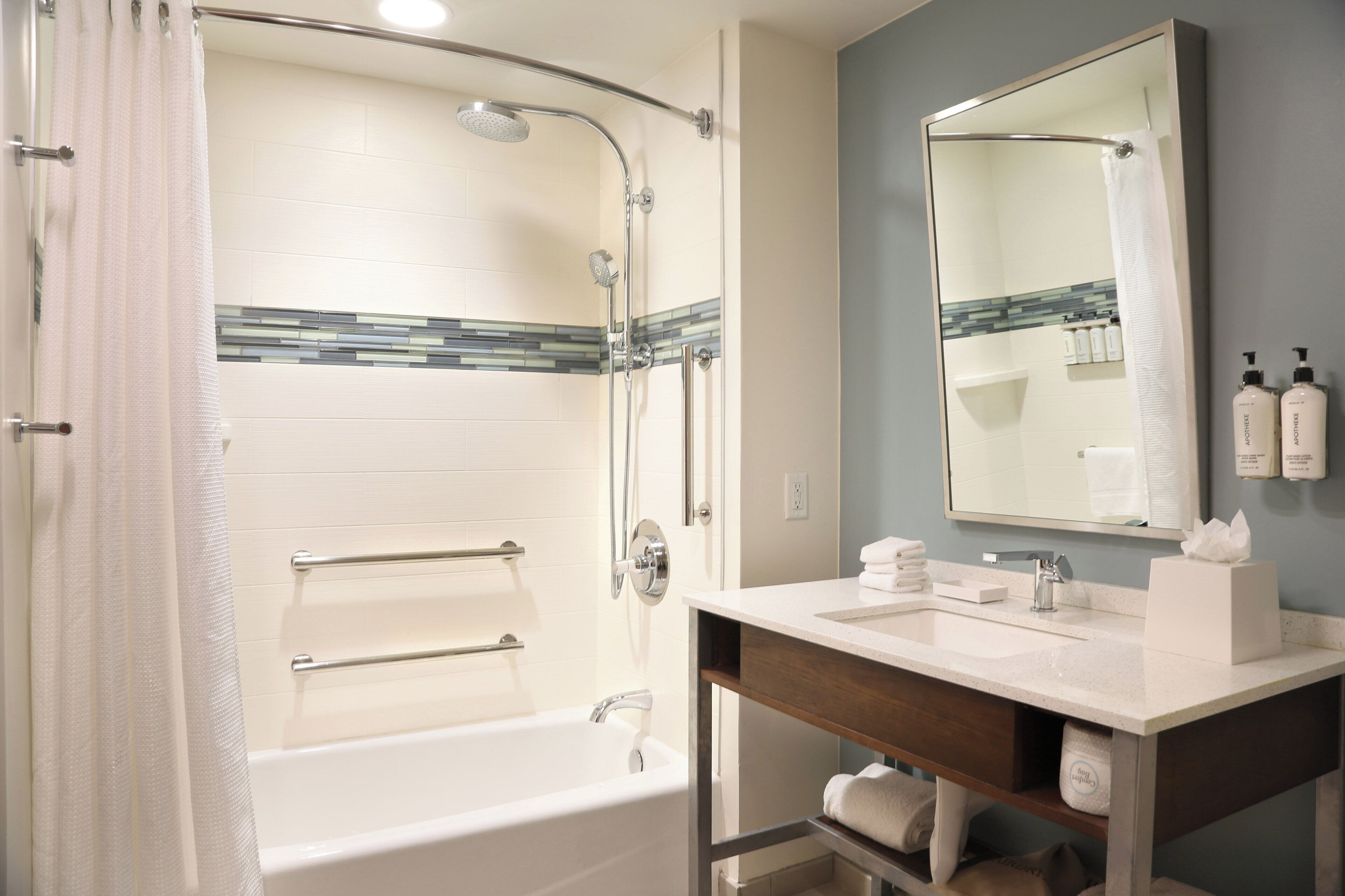 A bathroom with a bathtub, shower, vanity, and a mirror.
