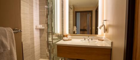 A modern bathroom with a glass shower enclosure, a wooden vanity with a mirror, and a towel rack.
