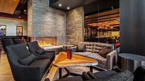 A modern lounge area with dark-toned seating, a central coffee table, and a stone accent wall. - Sycuan Casino Resort (El Cajon)