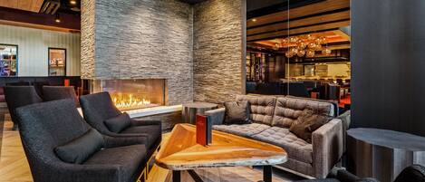 A modern lounge area with dark-toned seating, a central coffee table, and a stone accent wall.