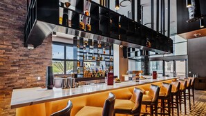 A modern bar area with a long counter, multiple stools, and a variety of bottles on shelves. - Sycuan Casino Resort (El Cajon)