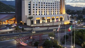 A modern hotel with a prominent entrance, multiple floors, and a landscaped area with palm trees and a bridge. - Sycuan Casino Resort (El Cajon)