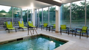 An indoor swimming pool with clear glass walls, green chairs, and a tiled floor. - SpringHill Suites by Marriott Elizabethtown (Elizabethtown)