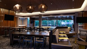 A modern hotel lobby with a large dining area, comfortable seating, and large windows offering a view of the outdoors. - SpringHill Suites by Marriott Elizabethtown (Elizabethtown)