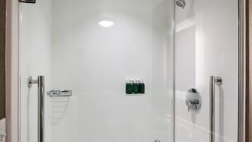 A glass-enclosed shower with a handheld showerhead, a glass door, and a towel rack.