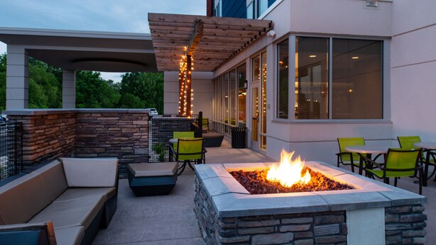 An outdoor patio with stone seating, a fire pit, and string lights. - SpringHill Suites by Marriott Elizabethtown (Elizabethtown)