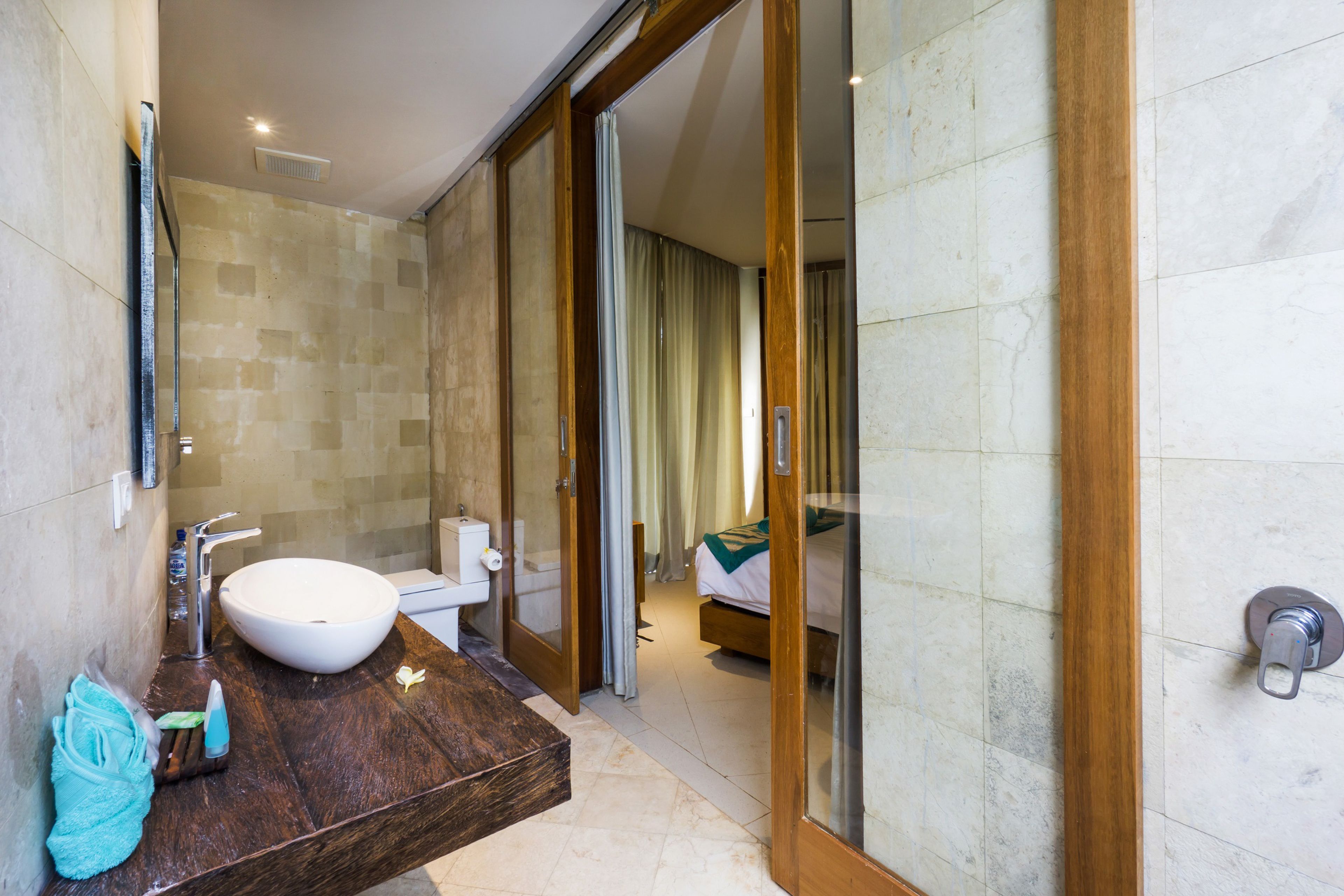 A modern bathroom with a large sink, mirror, and wooden vanity.