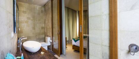 A modern bathroom with a large sink, mirror, and wooden vanity.