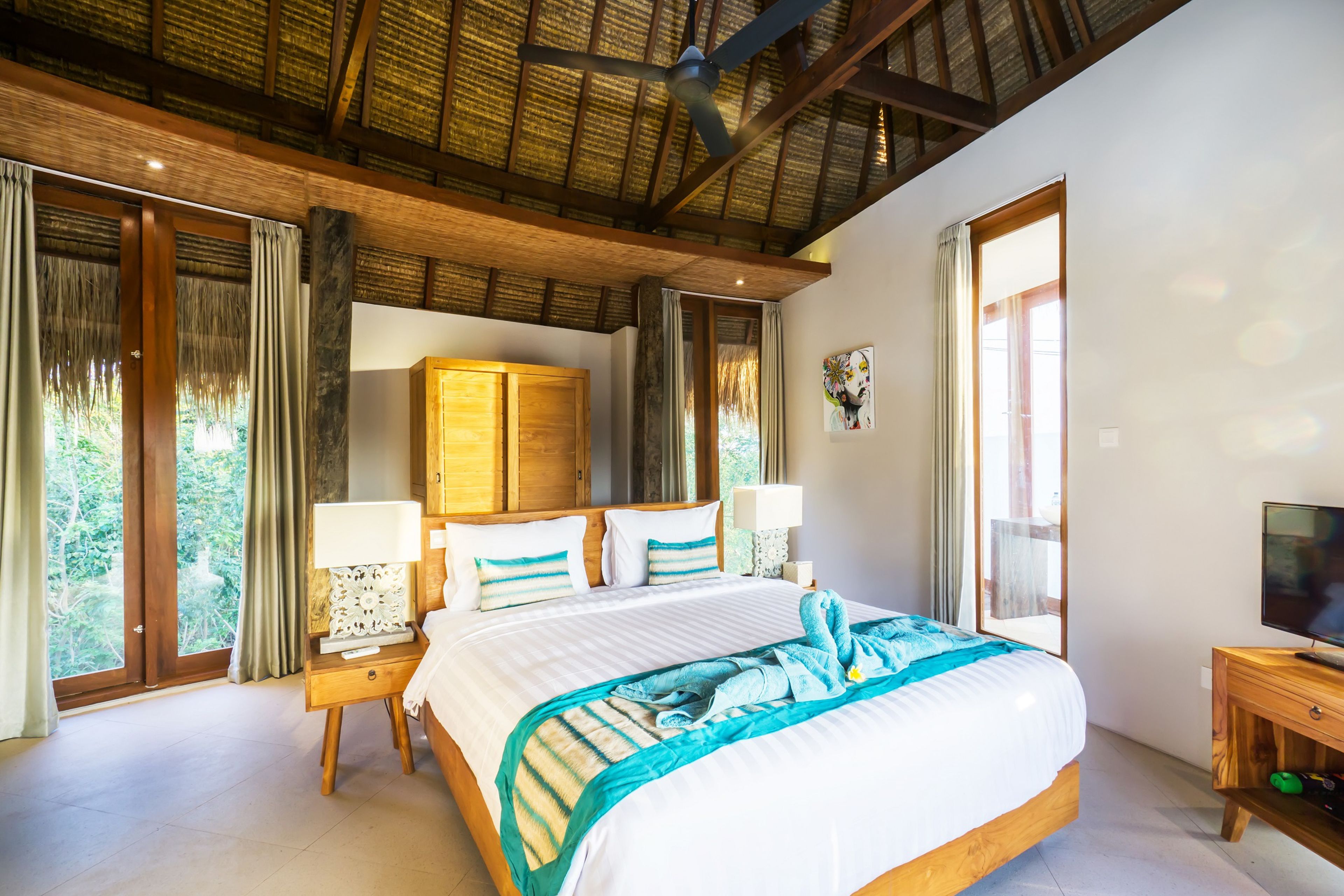 Ein geräumiges Schlafzimmer mit einem großen Bett, einem Holzkopfbrett und einem Deckenventilator.