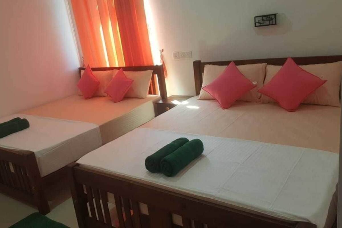 A hotel room with two single beds, a wooden headboard, and a small table with a green towel.