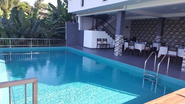 Una piscina con solárium, una escalera y mobiliario exterior.