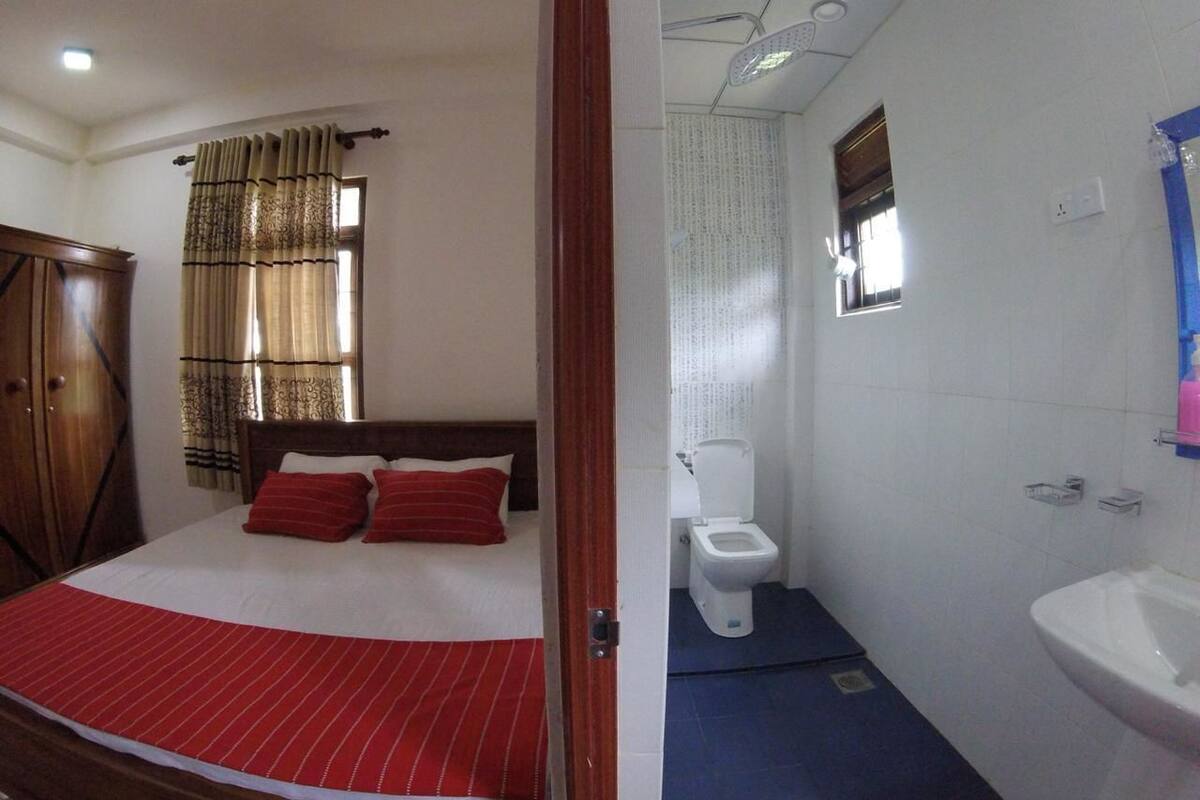 A bedroom with a bed, a wardrobe, and a bathroom with a toilet and sink.