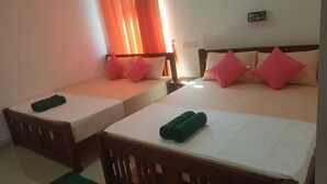 Habitación de hotel con dos camas individuales, cada una con cabecero de madera y ropa de cama blanca. Hay almohadas rosas y verdes sobre las camas.