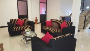 Un salón moderno con sofás a rayas, cojines rojos y una mesa de centro de vidrio.