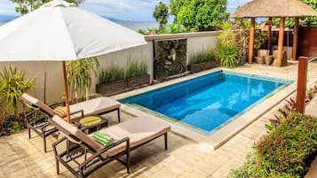 Una piscina al aire libre, sombrillas, sillones reclinables de piscina