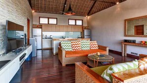 A modern kitchen with a dining area, a sofa with patterned cushions, and a ceiling fan. - Villa Agung (Lembongan Island)