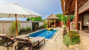 A poolside area with lounge chairs, a thatched-roof gazebo, and a dining area. - Villa Agung (Lembongan Island)