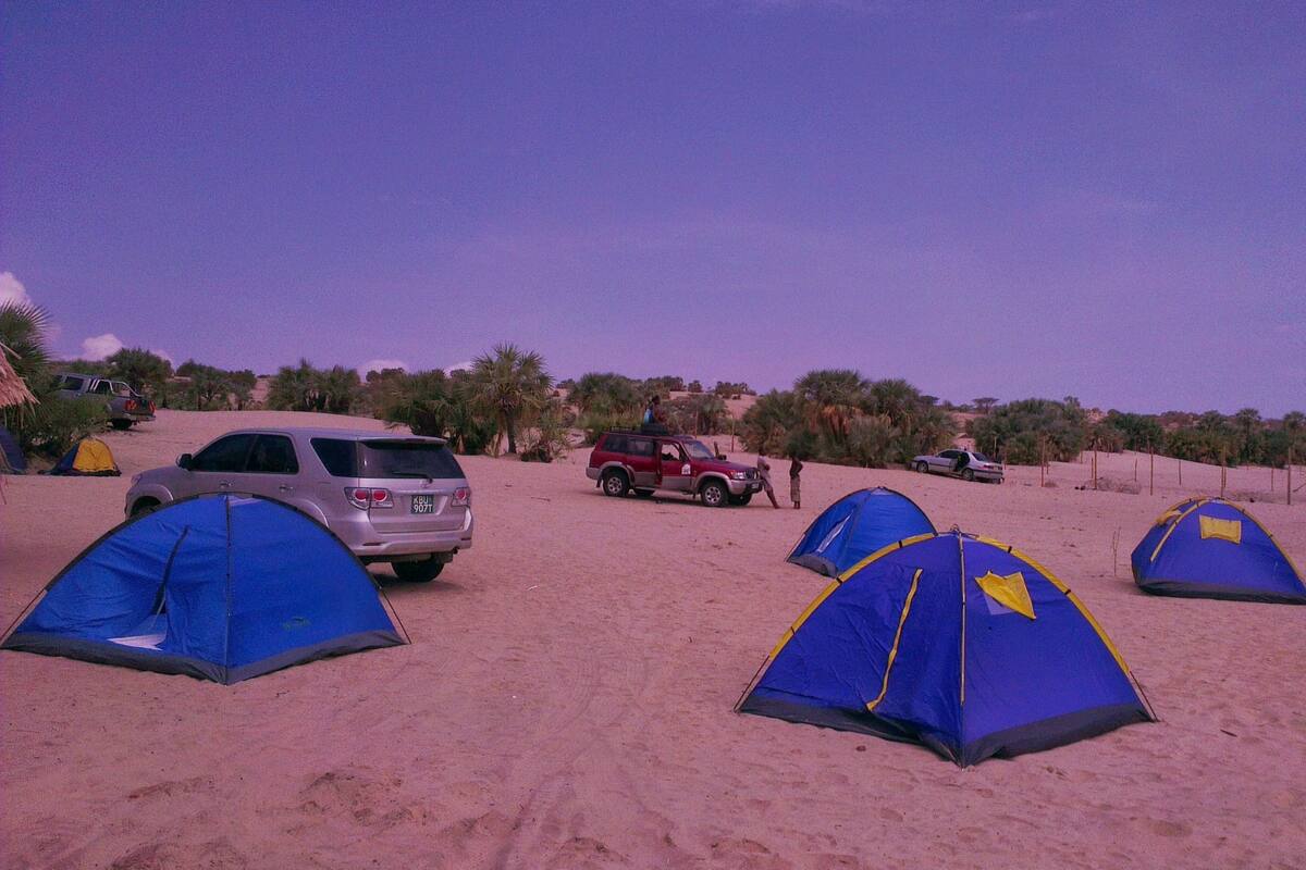 En campingplats i öknen med flera tält och fordon.