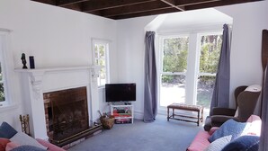 Ein Wohnzimmer mit Kamin, Fernseher, Sofa und Sessel.