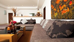 A modern living room with a sofa, coffee table, and a painting of flowers. - Romanee2 Convenient for life private pool Villa (Tambon Rawai)