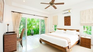 A spacious bedroom with a large bed, a ceiling fan, a desk, and a view of greenery through the glass door. - Romanee2 Convenient for life private pool Villa (Tambon Rawai)