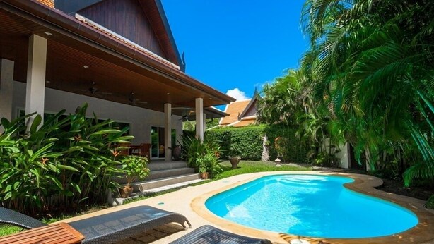 A swimming pool with lounge chairs, surrounded by lush greenery and a covered patio area. - Romanee2 Convenient for life private pool Villa (Tambon Rawai)