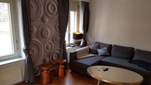 A modern living room with a grey sofa, a round coffee table, and two copper side tables. - New:Lovely 2.5 Room , Dish Washer, Wifi, Fully Equiped, own washer/dryer (Zürich)