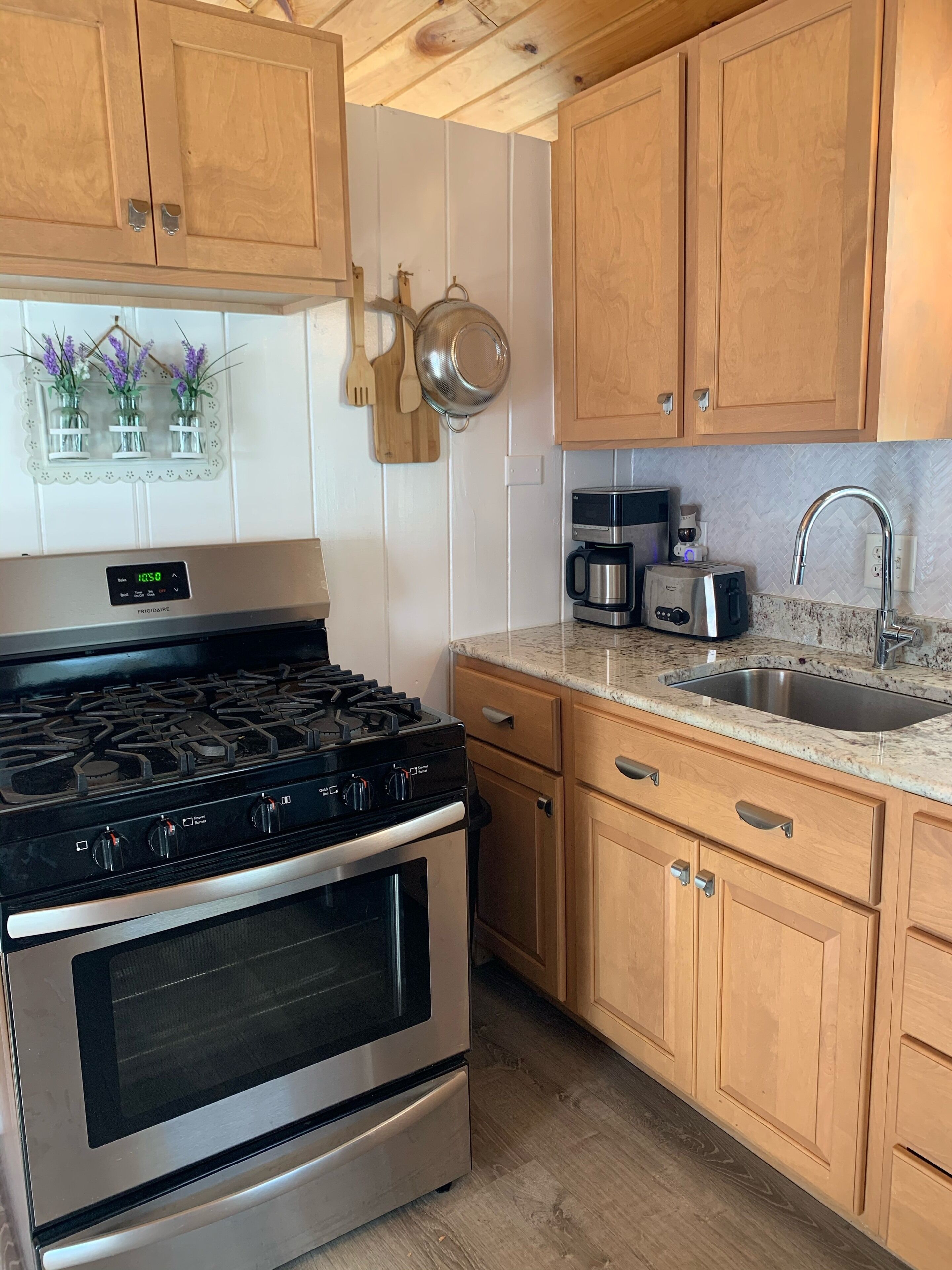A kitchen with wooden cabinets, a stainless steel stove, a coffee maker, and a toaster.