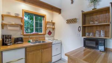 Una cocina compacta con armarios de madera, estufa, pileta y microondas.